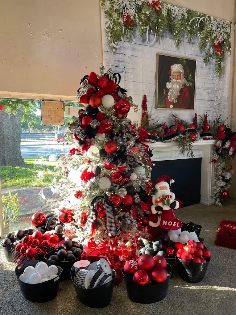 A red and silver themed tree beside a fireplace and Santa portrait
